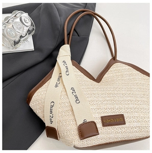 Detail of woven straw tote bag with brown leather trim and decorative branded ribbon