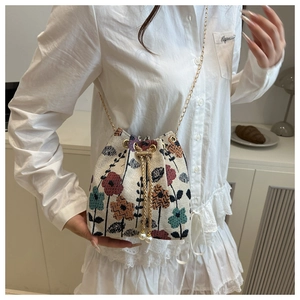 Detail of floral jacquard bucket bag featuring gold chain and double pearl drawstring