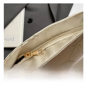 Detalle de cremallera dorada de primera calidad y estampado floral en bolso bandolera crema