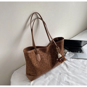 Detail of leopard print tote bag with brown plush monster charm and fine shoulder straps