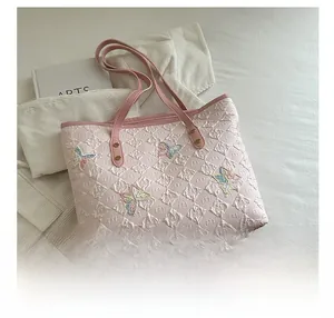 Dettaglio della borsa rosa con trapuntatura a rombi e ricami di farfalle colorate