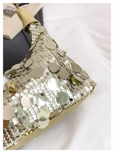 Macro detail of champagne gold sequin texture and leather handle on a chic handbag
