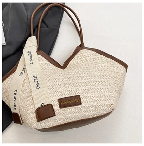 Detail of straw tote bag showing beige weave, dark brown leather trim and branded ribbon