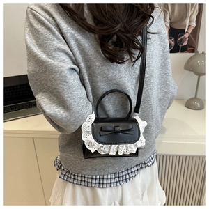 Mini borsa a tracolla nera con pizzo bianco e fiocco indossata da una modella