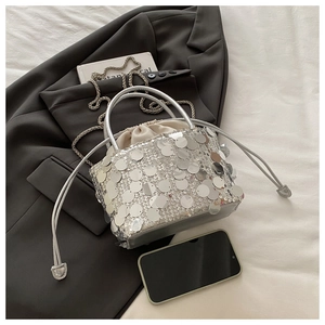 Detail of silver sequin bucket bag with drawstring closure and metal chain strap