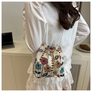 Detail of floral bucket bag featuring gold chain strap and pearl drawstring charms