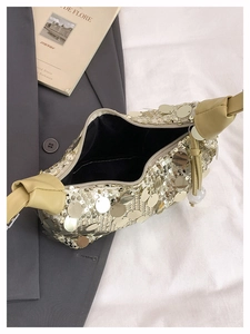 Close-up of golden sequin handbag with leather handle and black fabric inner lining