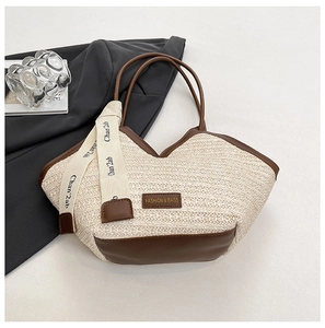 Detail of beige straw tote bag with brown faux leather trim and decorative ribbon strap