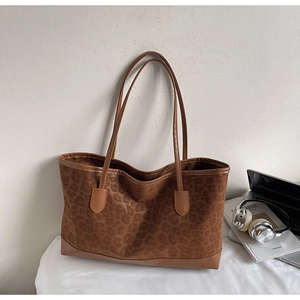 Detail of leopard print tote bag with brown leather handles and spacious interior