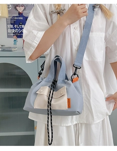 Détail d'un sac cabas en toile bleu et beige avec bandoulière large sur un mannequin