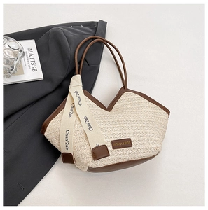 Detail view of woven straw tote bag featuring brown leather trim and stylish logo patches