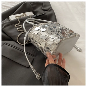 Detail of silver sequin bucket bag featuring metallic texture and drawstring closure
