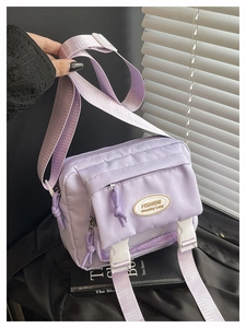 Detail of lavender nylon crossbody bag showing multiple pockets and stylish buckles