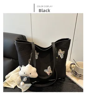 Detail of black jacquard tote bag featuring butterfly sequins and a white plush charm