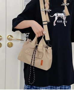 Détail du sac cabas en nylon beige avec fermeture à cordon et étiquette orange