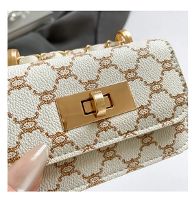Close-up of light gold twist lock and chain strap on white monogram textured leather bag
