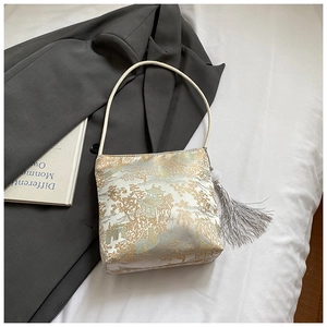 Detail of white brocade fabric with golden traditional patterns and silver tassel charm