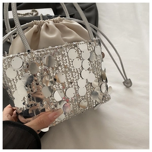Detail of silver sequin bucket bag with satin drawstring closure and chain strap