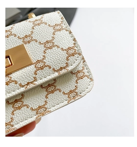 Close-up of white pebble leather crossbody bag with brown pattern and gold metal clasp