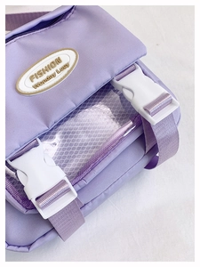 Detail of purple crossbody bag featuring white buckle straps and functional mesh pockets