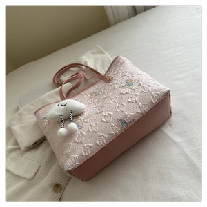 Détail du sac cabas rose avec texture matelassée, broderie papillon et pendentif nuage