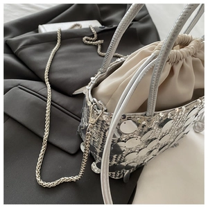 Detail of silver sequin bucket bag featuring a silk drawstring lining and chain strap