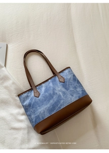 Detail of blue tie-dye tote bag with brown leather handles on minimalist background