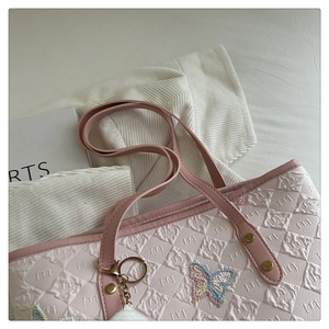 Gros plan du sac cabas rose avec broderie papillon et pendentif boule de peluche