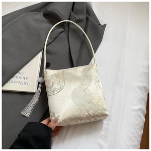Detail of silk satin handbag featuring Chinese bamboo patterns and a long silver tassel