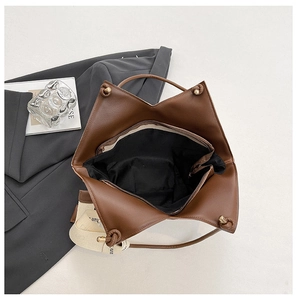Detail of large brown tote bag with woven shoulder strap and golden ball clasp