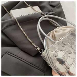 Close-up of silver sequin bucket bag featuring drawstring closure and metal chain strap