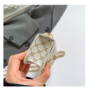 Detail of white square bag with cartoon pattern showing accordion side and gold chain