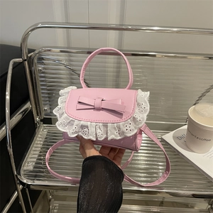 Pink mini square bag with lace trim and bow accent shown in a lifestyle hand-held pose