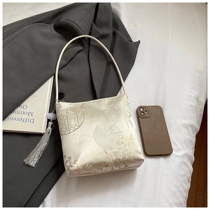Detailed embroidery of floral lattice patterns on beige satin shoulder bucket bag