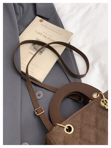 Detail of brown quilted faux leather texture with elegant diamond stitching and gold hardware