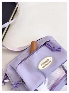 Detail view of purple canvas crossbody bag with multiple zip pockets and mesh layer