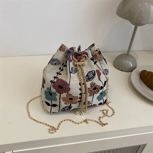 Ethnic floral drawstring bucket bag with gold chain strap and pearl accents