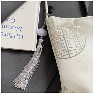 Detail of floral embroidery on cream satin bag with silk tassel and beaded charm