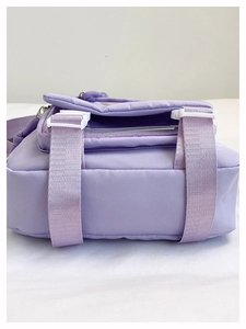 Detail of light purple messenger bag showing buckle closure and durable woven strap