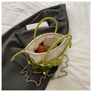 Detail view of neon green sequin bucket bag with chain strap showing spacious interior