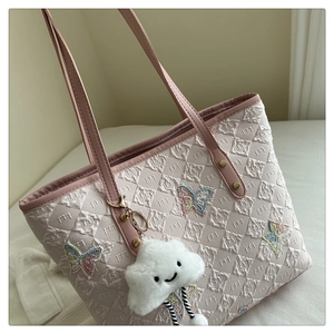 Gros plan du sac fourre-tout rose avec broderie papillon et charm nuage blanc