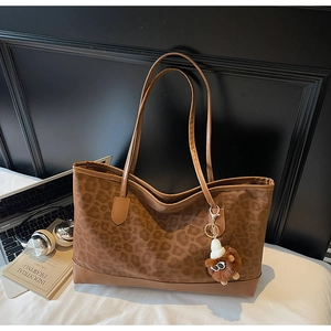 Detailed view of leopard print tote bag with brown bear charm and daily lifestyle items