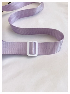 Detail of light purple woven shoulder strap with white adjustable buckle on white background
