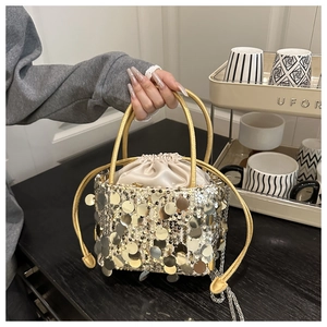 Detail of gold sequin bucket bag featuring drawstring closure and metal ring handle