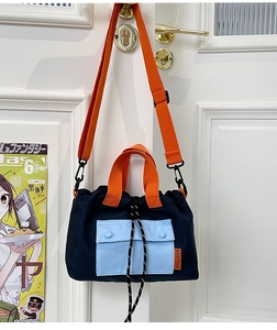 Détail du sac fourre-tout en nylon bicolore avec poignées orange et cordon de serrage