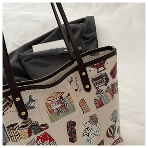 Détail d'un grand cabas beige avec illustrations de voyage et anses en cuir marron