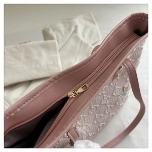 Gros plan d'un sac rose avec broderie de papillon et texture de logo en relief