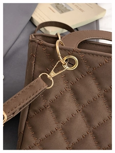 Close-up of brown quilted handbag featuring diamond stitching and gold metal hardware