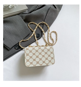 Detailed close-up of retro monogram pattern and gold chain strap on white crossbody bag