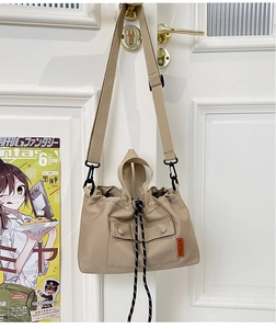 Détail du sac fourre-tout en nylon beige avec cordon de serrage et étiquette orange